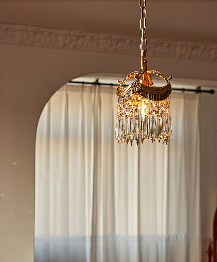 Pendant light with French velvet tassels and crystal prisms, casting soft light in a neutral-toned living space.