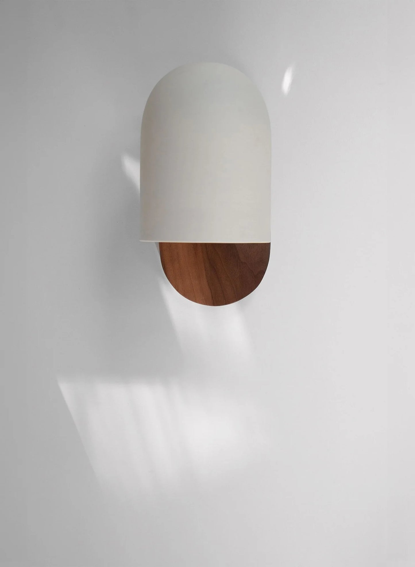 Front view of LUXELY white dome wall sconce with walnut wood base, casting soft light for minimalist home décor.