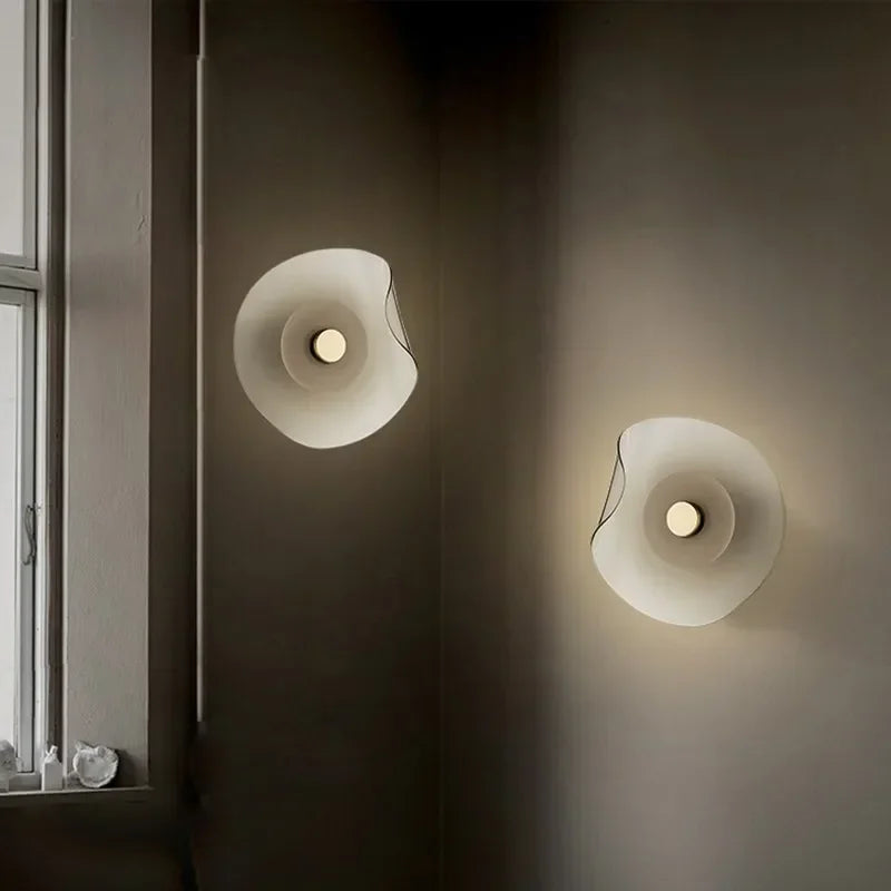 Pair of modern glass wall lamps with art deco round design illuminating a hallway or living room with warm ambient light.