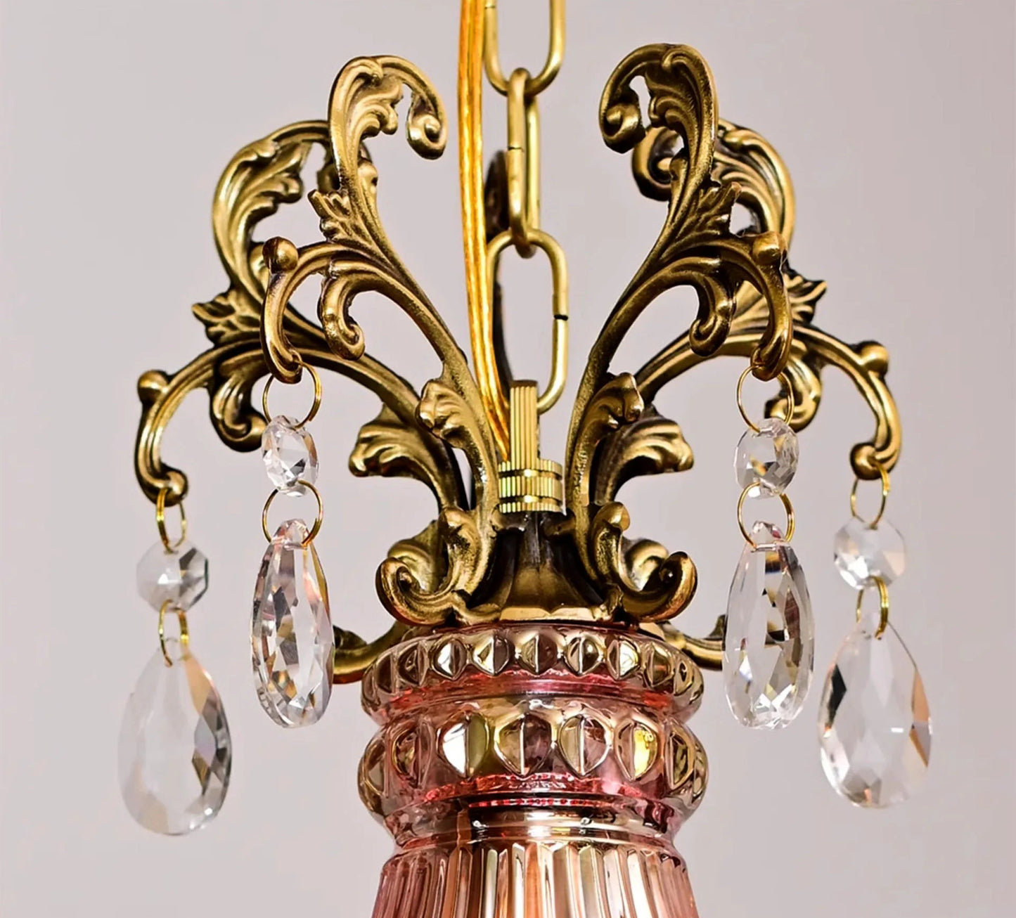 Close-up of gold scroll detailing and crystal drops on retro French chandelier, luxury pendant light craftsmanship.