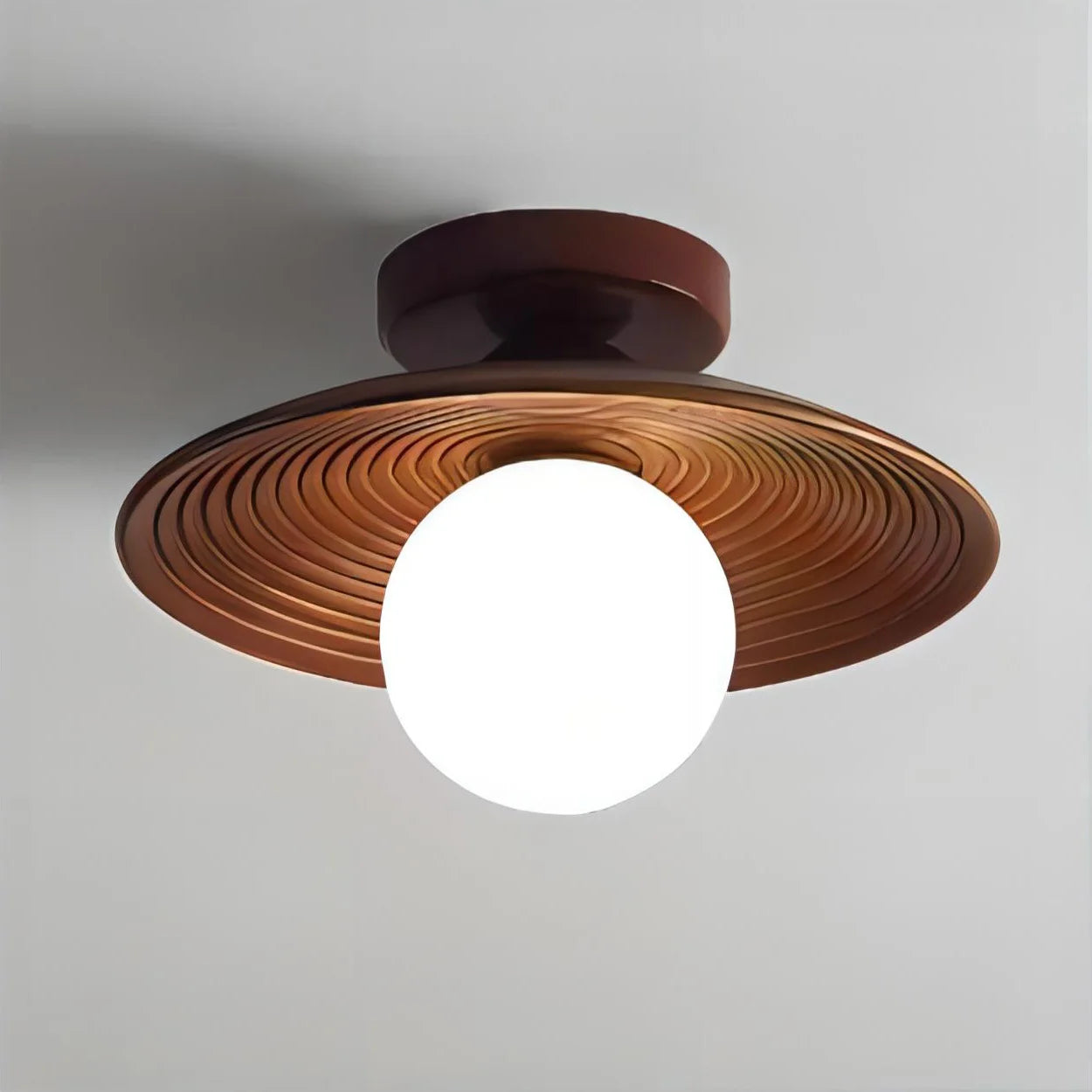 Modern flush mount ceiling light with carved walnut wood shade and frosted globe bulb, ideal for minimalist interiors.