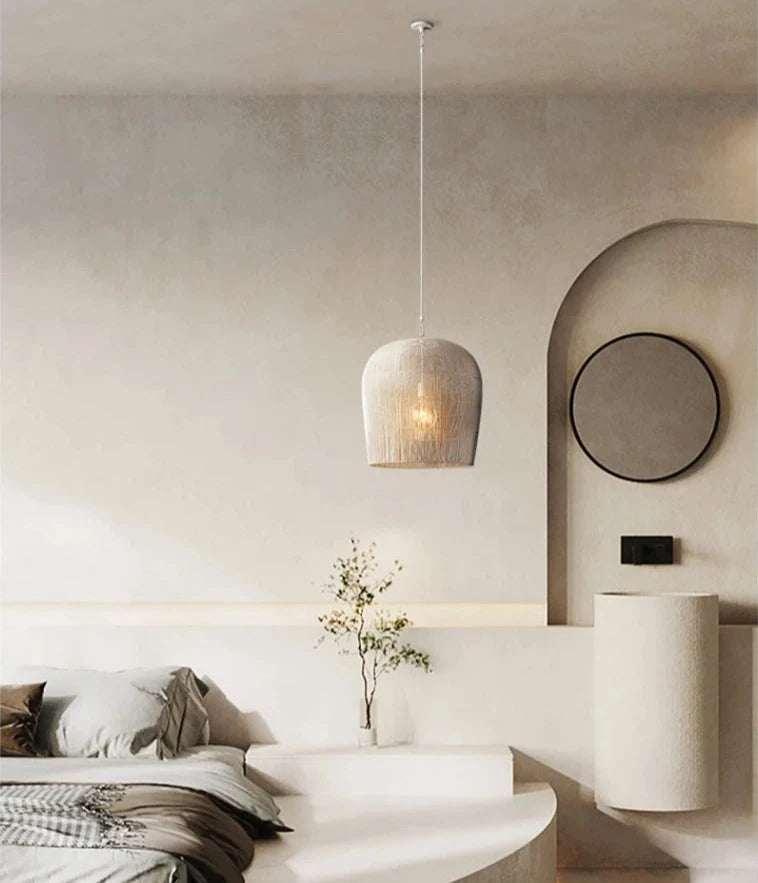 White LUXELY handmade rattan pendant light above a modern bed, adding soft, ambient lighting to a serene bedroom.