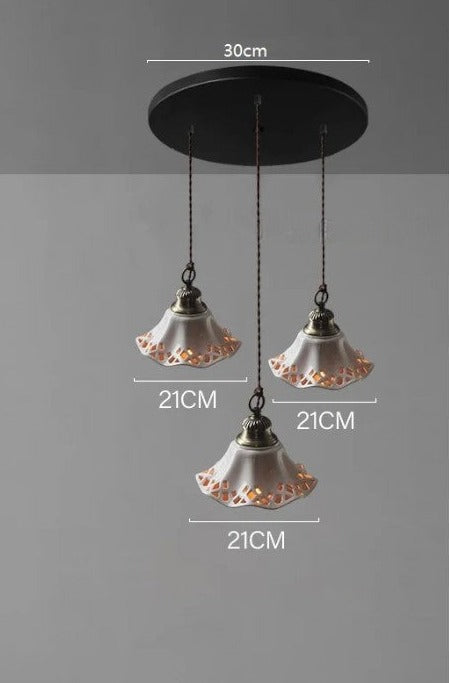 Triple white ceramic pendant lights with cut-out floral design on a 30cm round base, ideal for cozy dining areas.
