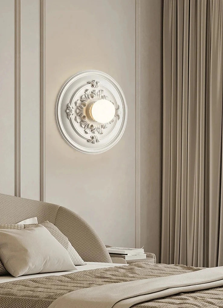 LUXELY round bedside wall lamp in white, softly illuminating a neutral-toned bedroom with classic elegance.