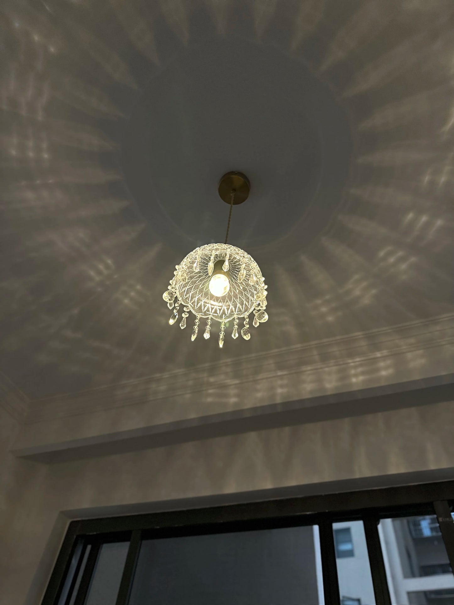 French Vintage Crystal Chandelier - Copper Hanging Lamp in modern room with large window and soft lighting.