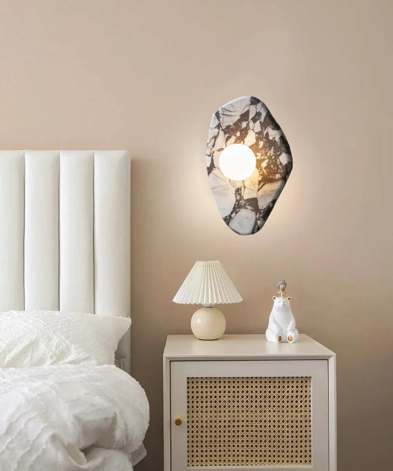G9 Stone Wall Light with glass globe sconce above a nightstand, offering soft lighting for a modern bedroom setup.