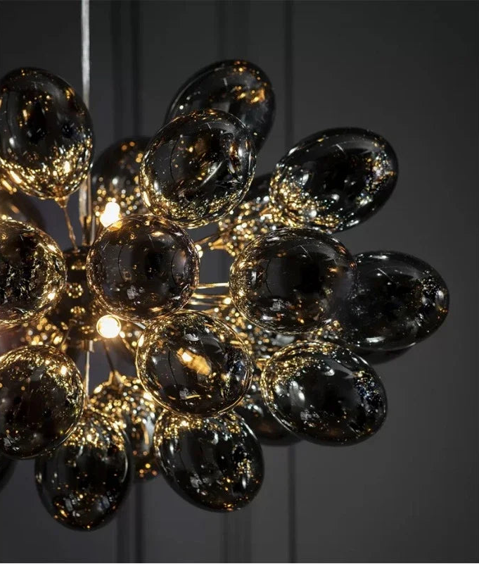 Close-up of modern grape glass chandelier showcasing reflective smoked glass bulbs and warm LED lights, perfect for luxury home lighting.