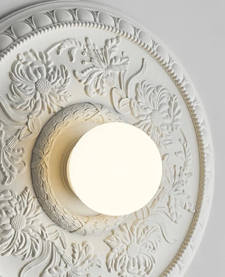 Detailed view of white LUXELY wall lamp with embossed floral design, ideal for elegant hallway or bathroom lighting.