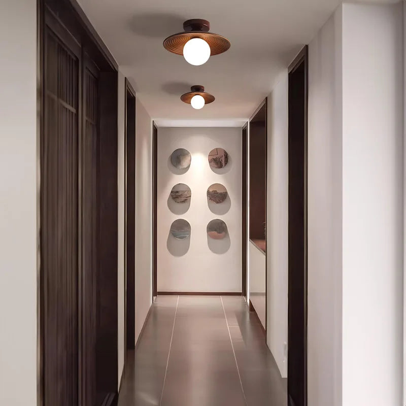 Modern hallway with two walnut wood and brass ceiling lights, showcasing a clean and elegant lighting solution for narrow spaces.