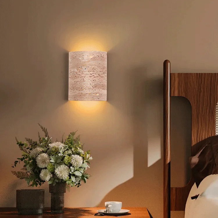 Warm-lit travertine wall lamp IP65 in bedroom, enhancing cozy ambiance with minimalist stone lighting.