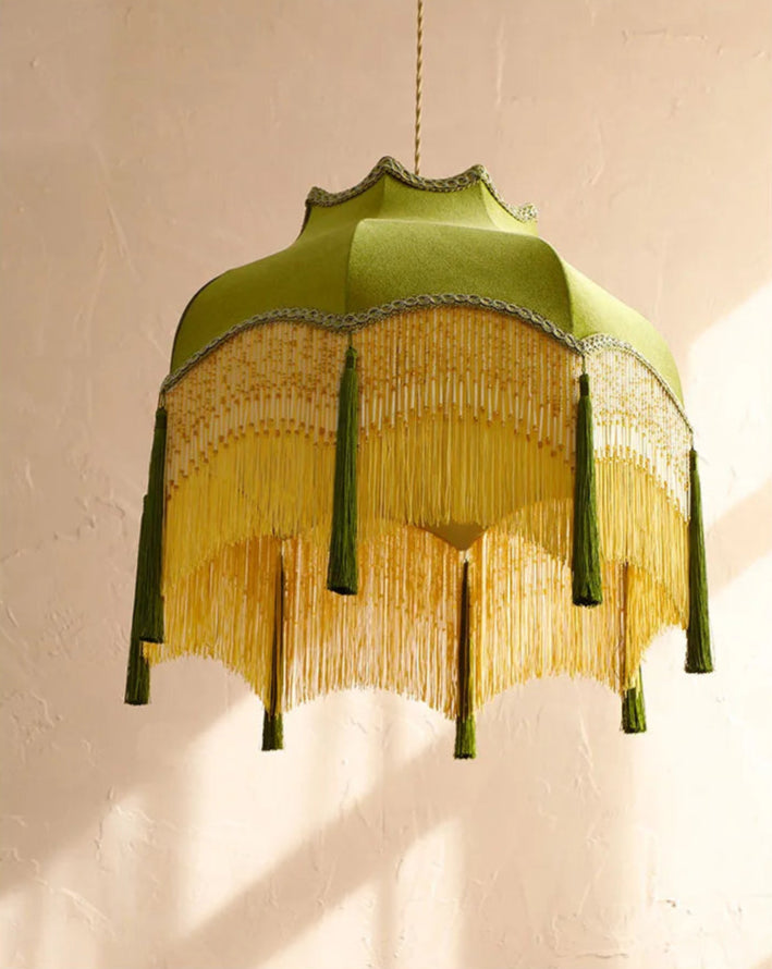 Detailed view of green velvet pendant light with ornate fringe, showcasing its scalloped edge and tassel design.