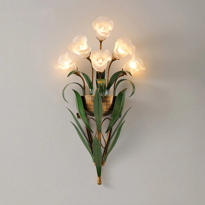 White flower French country wall light with green foliage, offering a soft glow for cozy and elegant interiors.