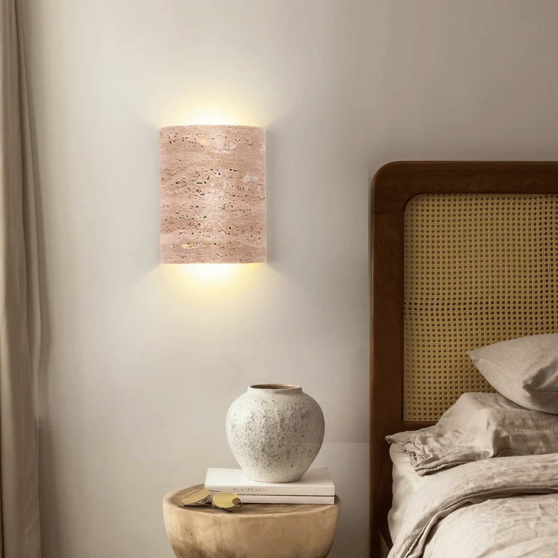 Bedroom setup with travertine wall lamp IP65 above nightstand, offering soft lighting and natural stone elegance.