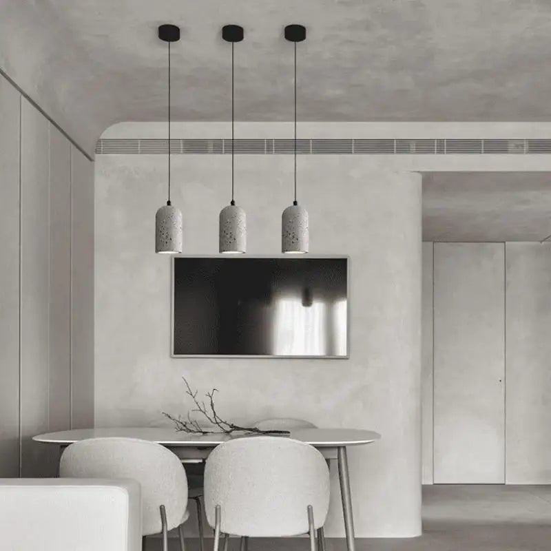 Three terrazzo cement pendant lights hanging in a minimalist dining room. LUXELY lighting fixture enhances modern home interiors.