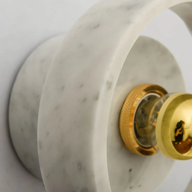 Macro view of the marble wall lamp's circular frame and gold LED bulb, showcasing its modern wabi-sabi aesthetic.