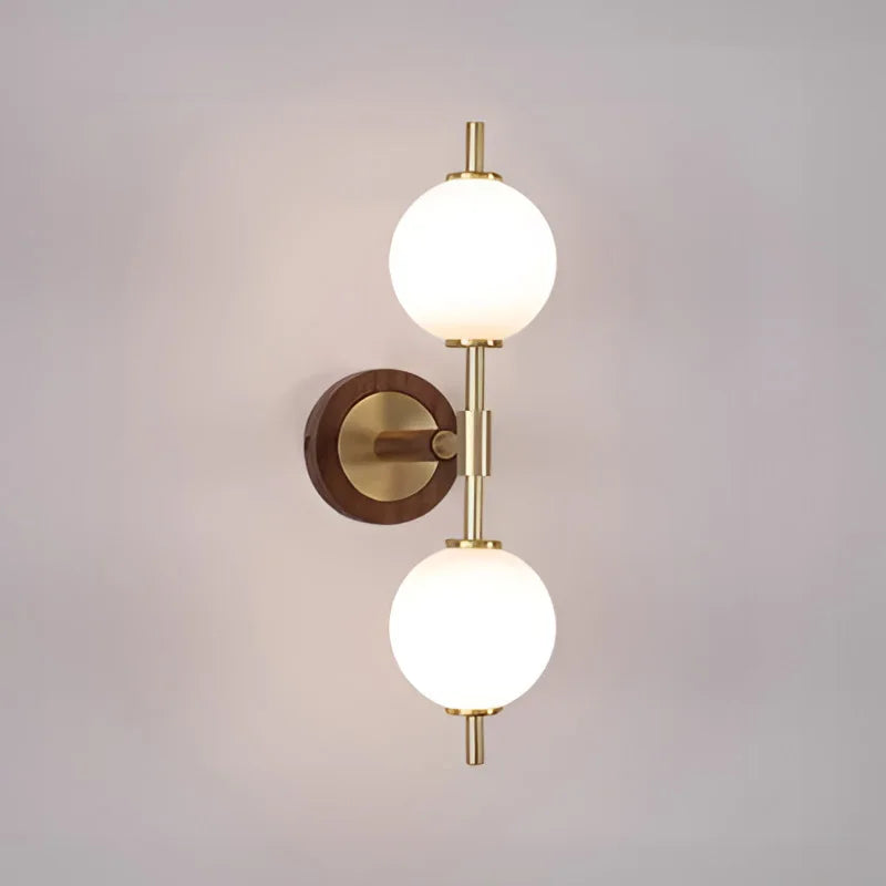 Modern brass and wood wall light fixture with two frosted glass globes, perfect for contemporary home decor.