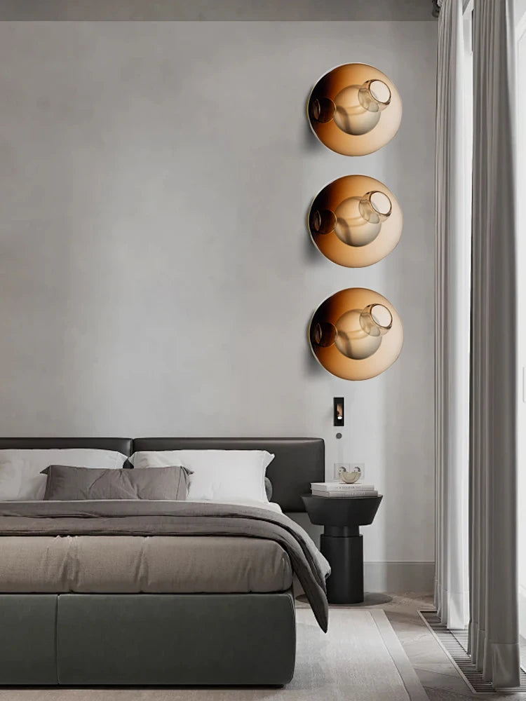 Italian designer LED wall lights in amber glass spheres arranged vertically in a modern bedroom, perfect for ambient lighting and décor.