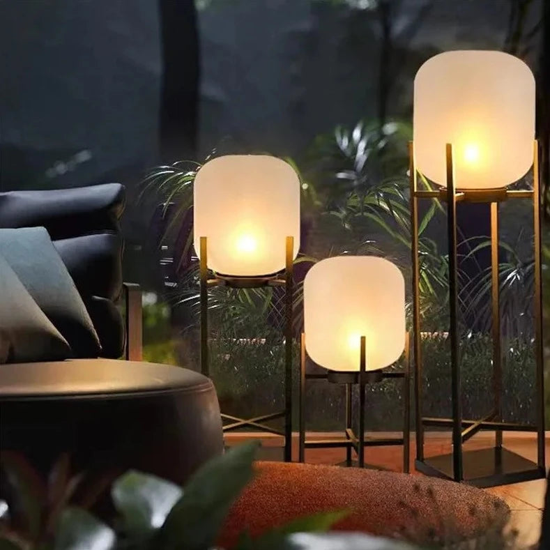 Three LUXELY waterproof outdoor solar lights glowing warmly in a cozy villa garden seating area.