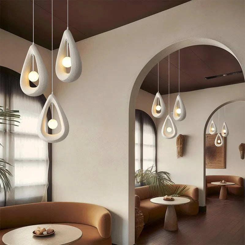 Teardrop-shaped Nordic wabi-sabi pendant lights in a cozy dining nook, offering soft LED lighting with a modern art deco aesthetic.