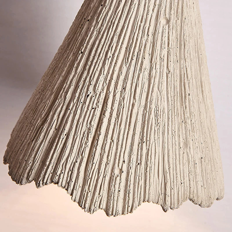 Close-up of textured travertine pendant lamp shade, showcasing natural grooves and handcrafted finish for organic lighting style.