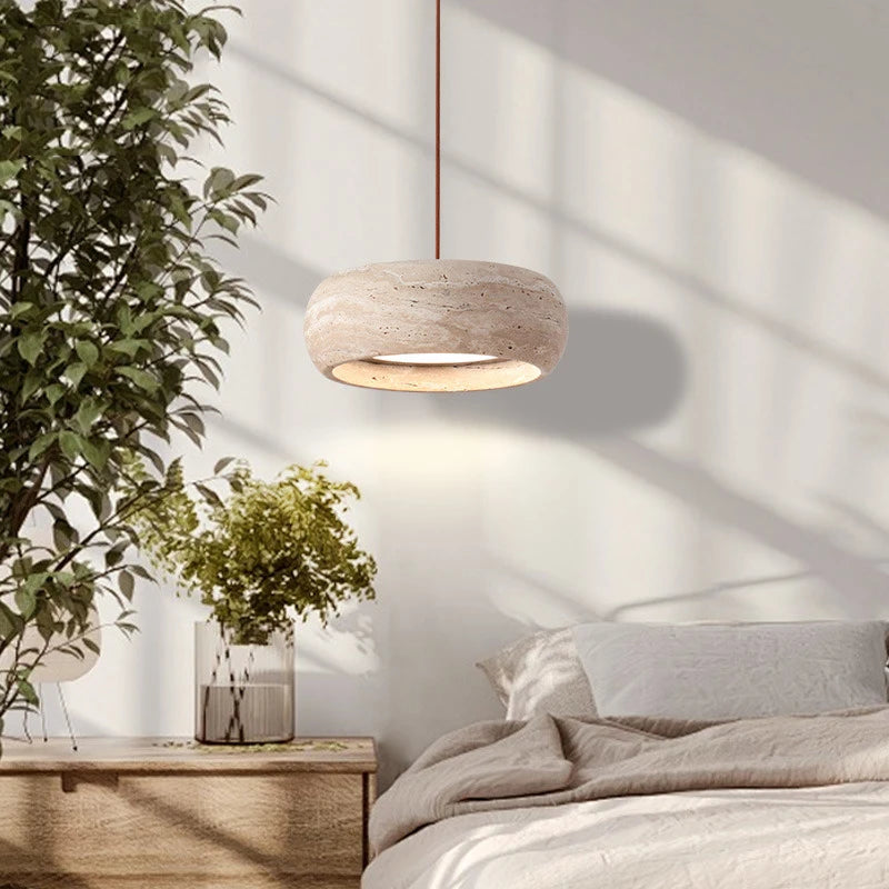 Travertine Stone LED Pendant Light – Modern Fixture hanging beside a bed, highlighting its soft glow and natural stone texture.