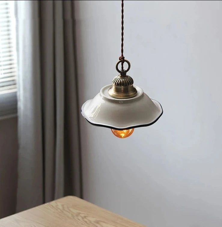 White ceramic pendant light with curved edge and amber bulb, ideal for vintage kitchen or dining room lighting.
