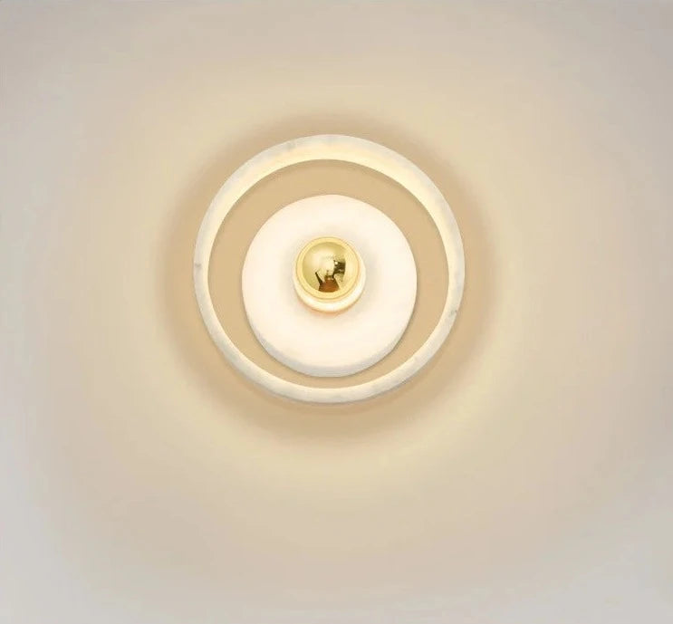 Front view of the marble round wall lamp glowing warmly, ideal for modern bedroom or hallway lighting ambiance.