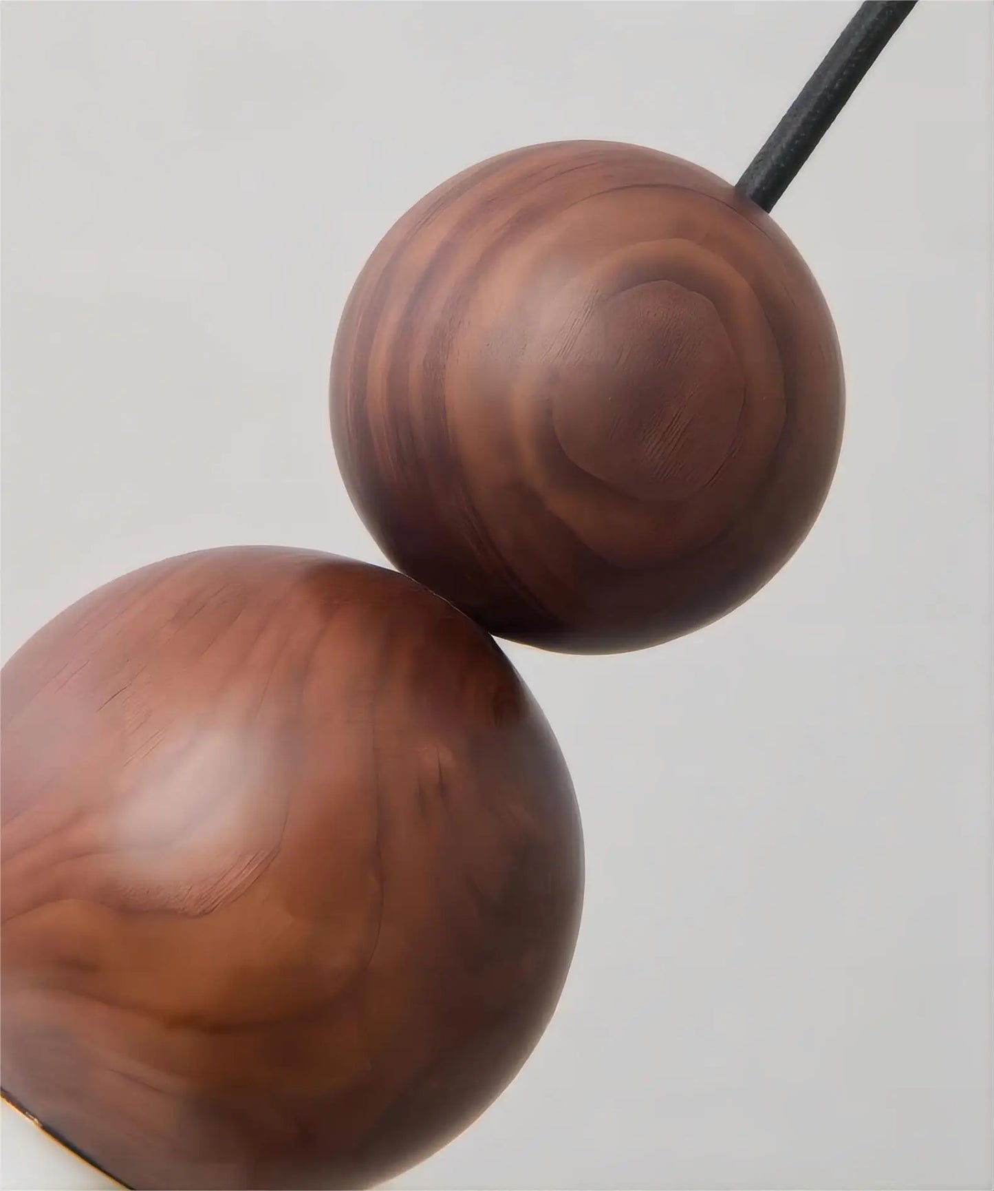 Close-up of walnut wood spheres on LUXELY wall light, highlighting natural grain and craftsmanship in modern lighting.