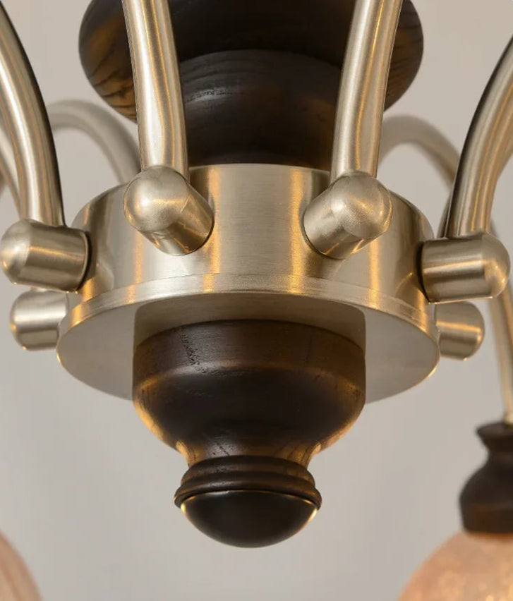 Close-up of the chandelier's brushed gold metal base and black wood accents, showcasing premium materials and build quality.