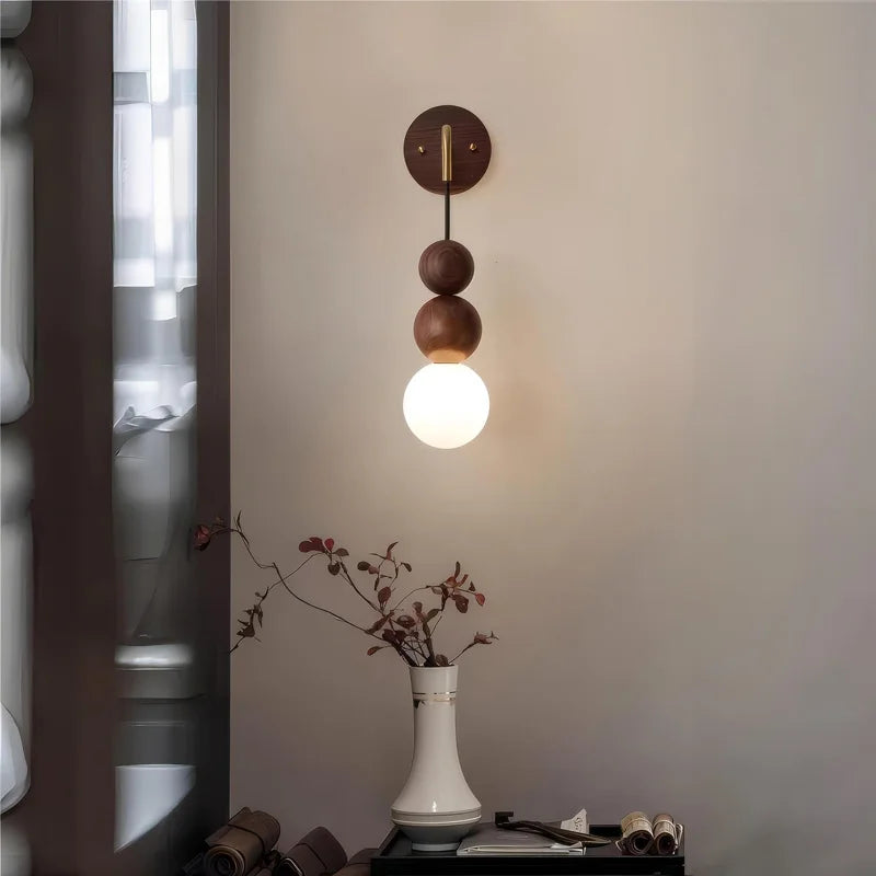 LUXELY walnut wood and brass wall light fixture with glowing glass globe, enhancing a serene living space with natural decor.