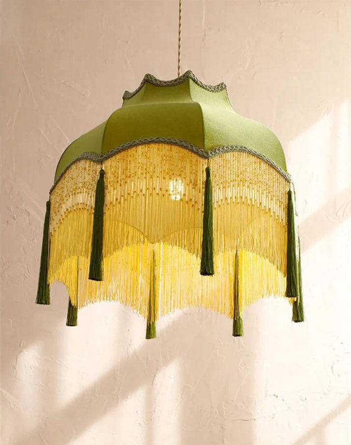 Close-up of luxury green velvet chandelier with layered gold fringe and tassels, ideal for vintage-inspired interiors.