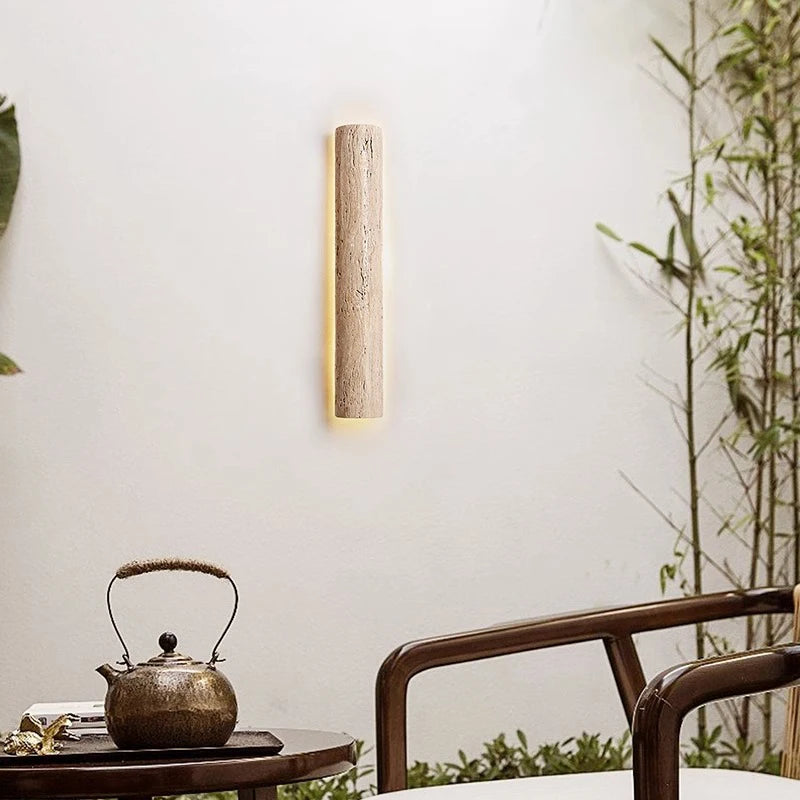 Rod-shaped IP65 travertine wall lamp lighting a cozy patio area, blending natural stone with modern outdoor design.