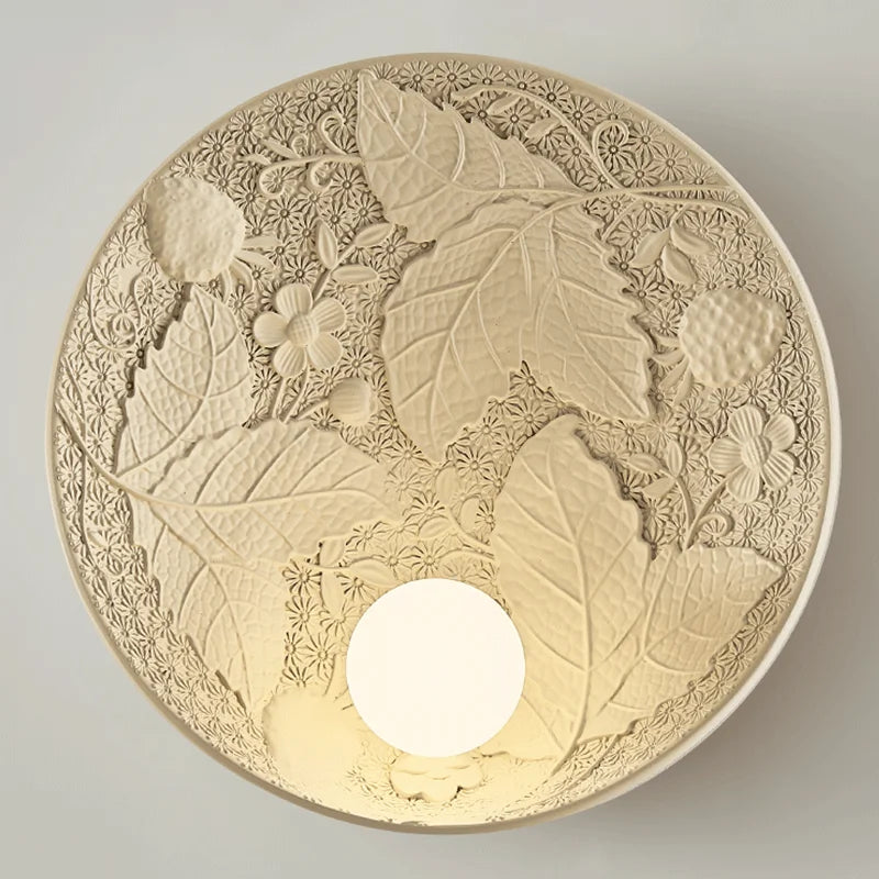 Close-up of vintage French wall lamp with embossed leaf and floral textures, round sconce for refined home or office lighting.