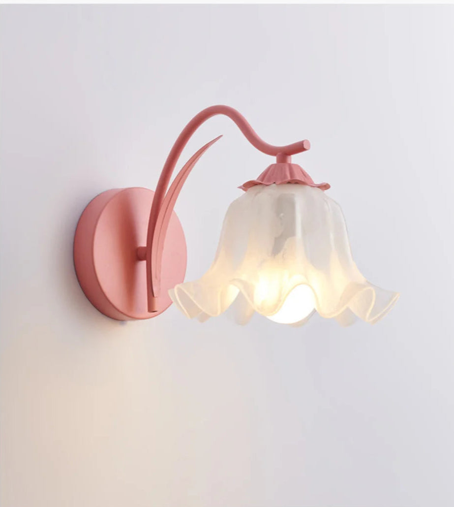 Close-up of pink French flower sconce with curved metal arm and ruffled glass shade, perfect for modern home decor lighting.