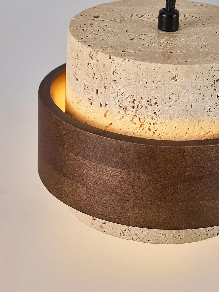 Close-up of travertine pendant lamp bedside with wood ring detail, highlighting wabi-sabi craftsmanship and soft ambient lighting.