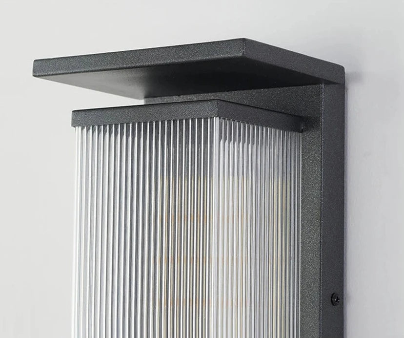 Close-up of stainless steel outdoor wall lamp showing ribbed diffuser and waterproof construction for modern exteriors.