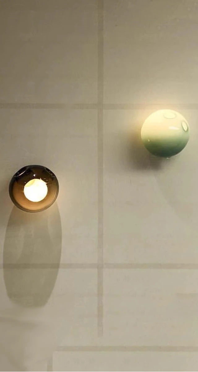 Minimalist wall with two colorful glass LED sconces, showcasing modern Italian design for artistic bedroom or café lighting.