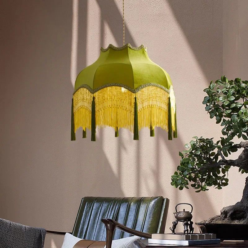 Green velvet pendant light with gold tassels hanging in a modern lounge, blending vintage charm with contemporary interiors.