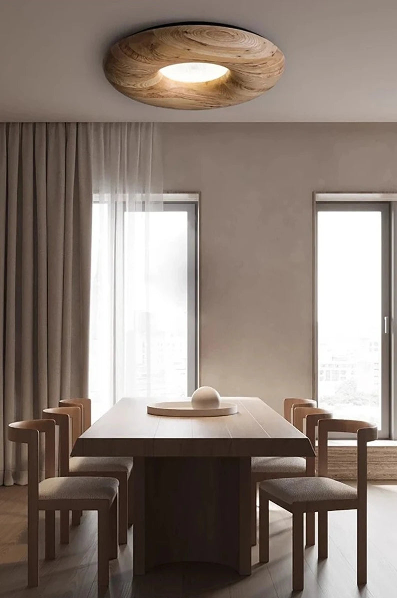 Dining area with large wooden table and LUXELY ceiling lamp, providing warm ambient lighting with a modern rustic touch.