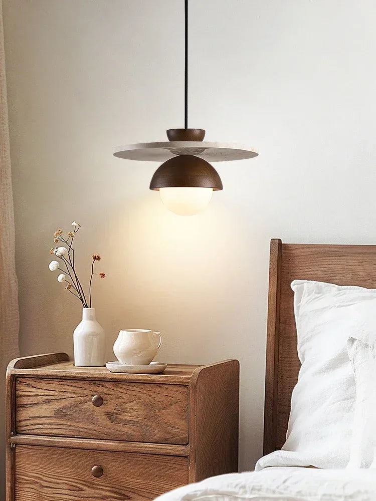 Walnut wood pendant light hanging over bedside table, minimalist bedroom lighting with stone and LED design.