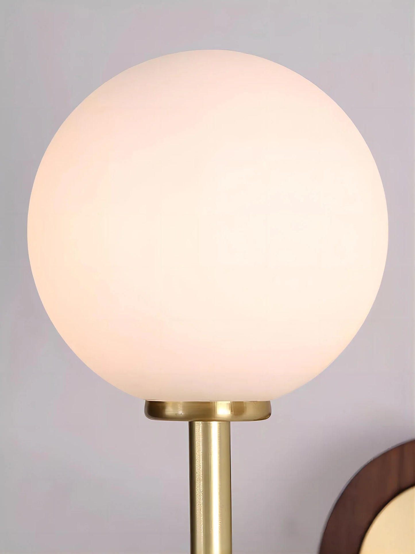 Frosted glass globe of LUXELY wall lamp, designed for soft diffusion of light in bedrooms, bathrooms, or hallways.