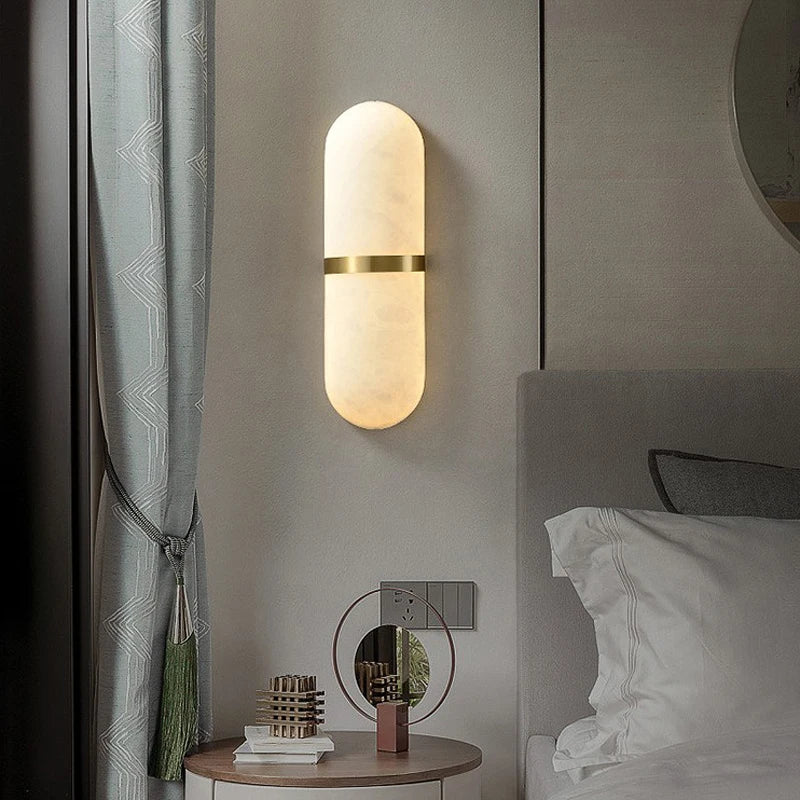 Luxury oval marble wall lamp with brass accent mounted beside bed, perfect for bedroom ambient lighting and modern decor.