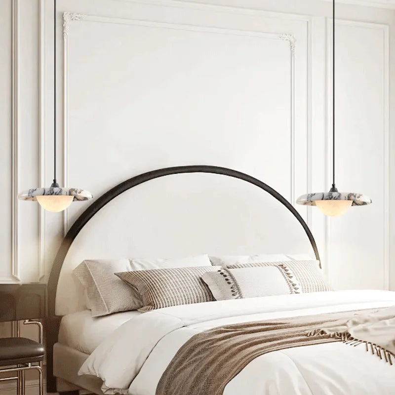 Pair of Matte Marble Pendant Lamps with black round design above a bed, enhancing bedroom ambiance with soft LED lighting.