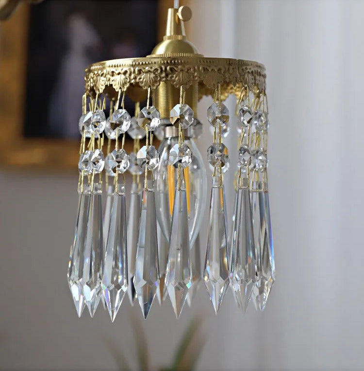 Crystal pendant detail of copper angel chandelier light, featuring intricate gold edging and LED illumination.