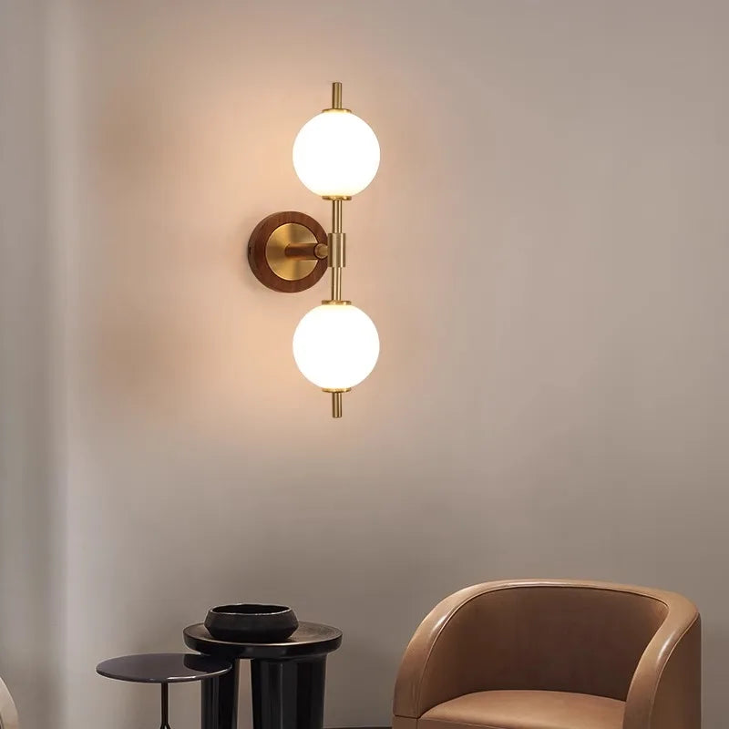 Modern copper bedroom sconce with dual globe lights, installed in a minimalist living room with neutral decor.