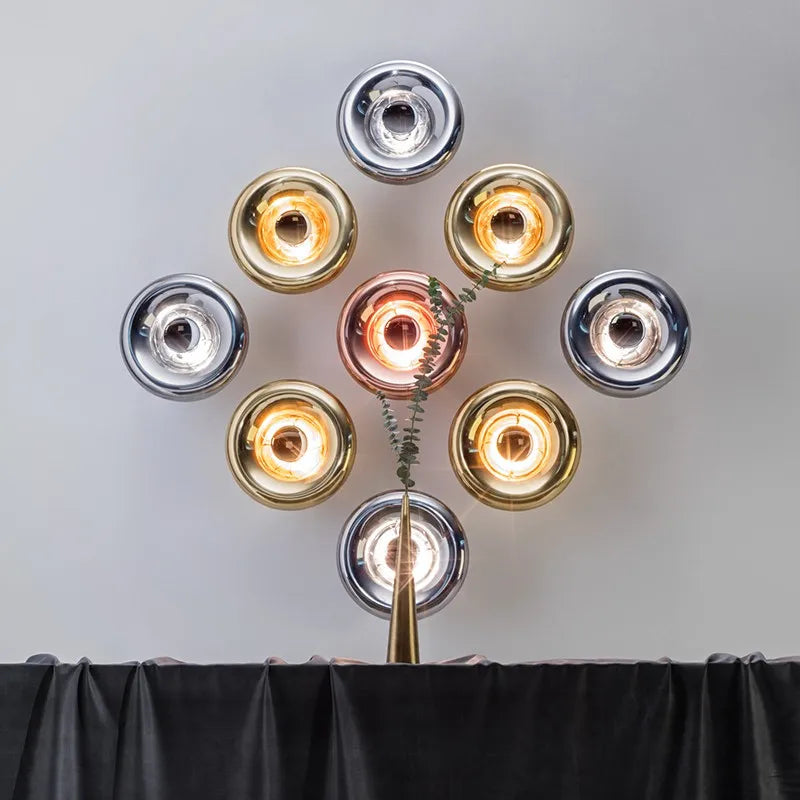 Cluster of silver, gold, and copper lava wall lamps arranged in a circular pattern above a console table.