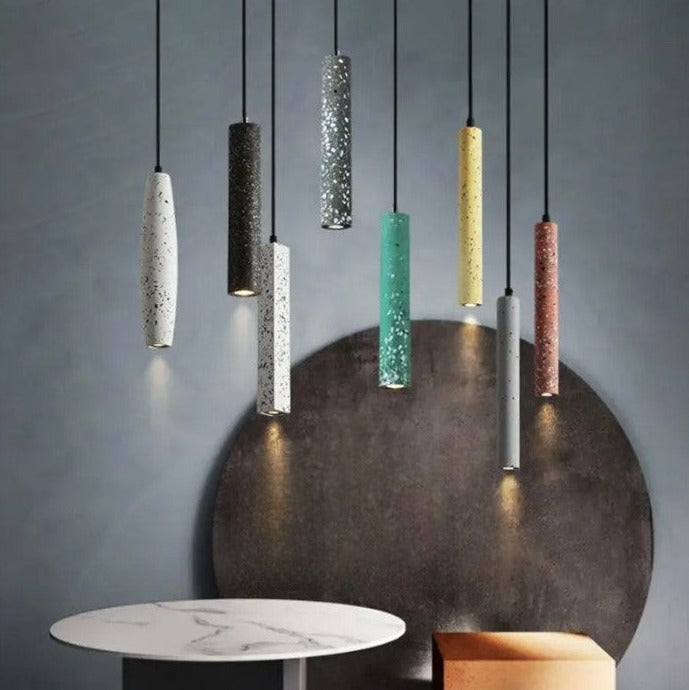 Colorful LUXELY industrial cement pendant lights hanging over a modern dining setup. LED lighting perfect for kitchen or restaurant decor.