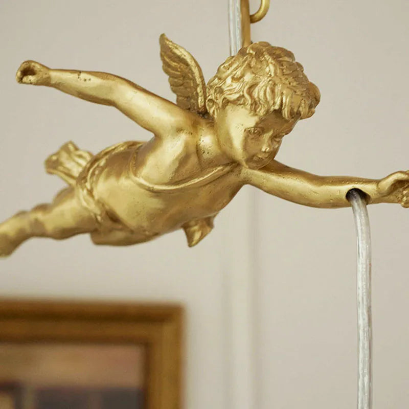 Close-up of copper angel figure on chandelier light, highlighting intricate craftsmanship and antique gold finish.