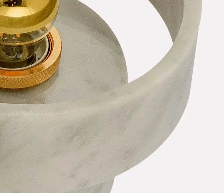 Detailed close-up of the marble texture and gold bulb socket of the round wall lamp, emphasizing quality craftsmanship.