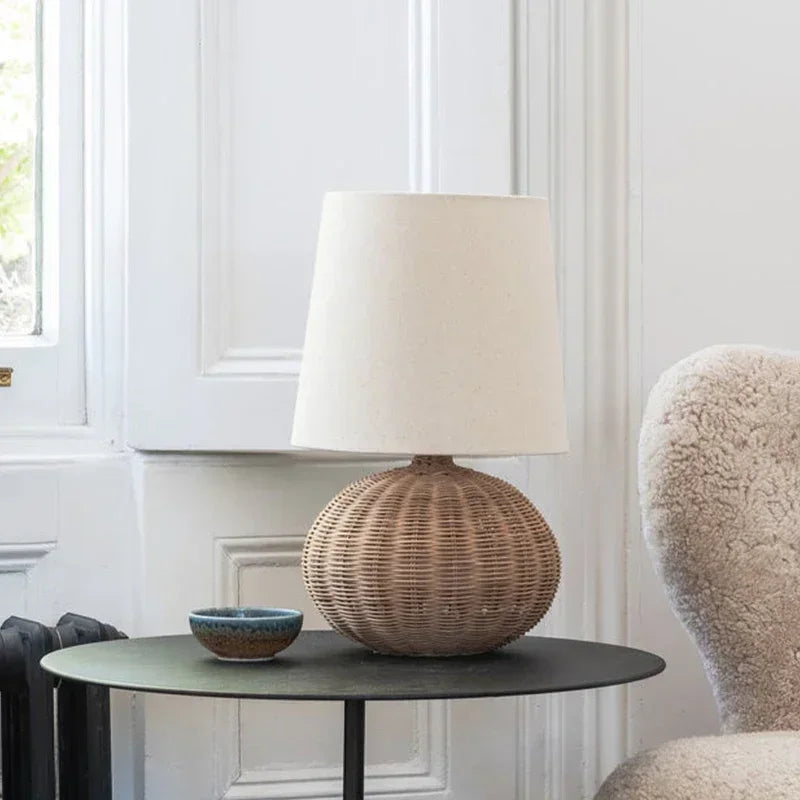 Japanese Wabi-sabi table lamp with round wicker base and fabric shade, styled on a black side table for modern bedroom decor.